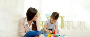 Autism & ABA: Children's Center for Autism: Therapist observes child playing with blocks on the floor