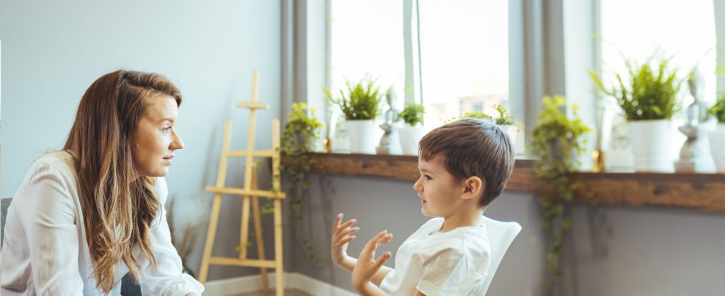 自闭症和 ABA 儿童服务中心：一位治疗师在说话时向一位年轻的男性患者倾斜