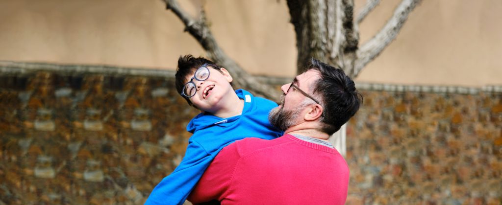 Child and Family Services: Father holding son close outside while they laugh together