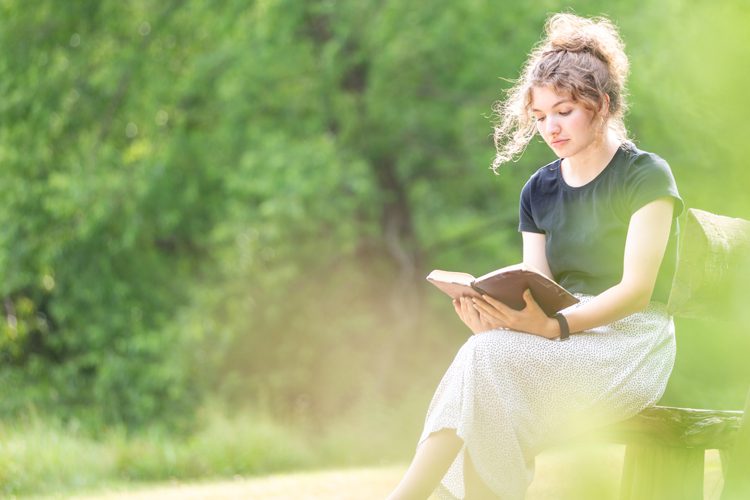 危機一時停止サービス: 外のベンチに座って本を読んでいる若い女性