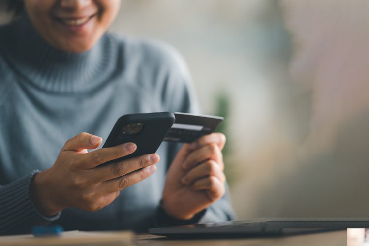 Servicios de salud mental para adultos: costo de los servicios ambulatorios de salud mental: una mujer con un teléfono móvil en una mano y una tarjeta de crédito en la otra