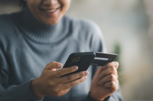 Servicios de salud mental para adultos: costo de los servicios ambulatorios de salud mental: una mujer con un teléfono móvil en una mano y una tarjeta de crédito en la otra